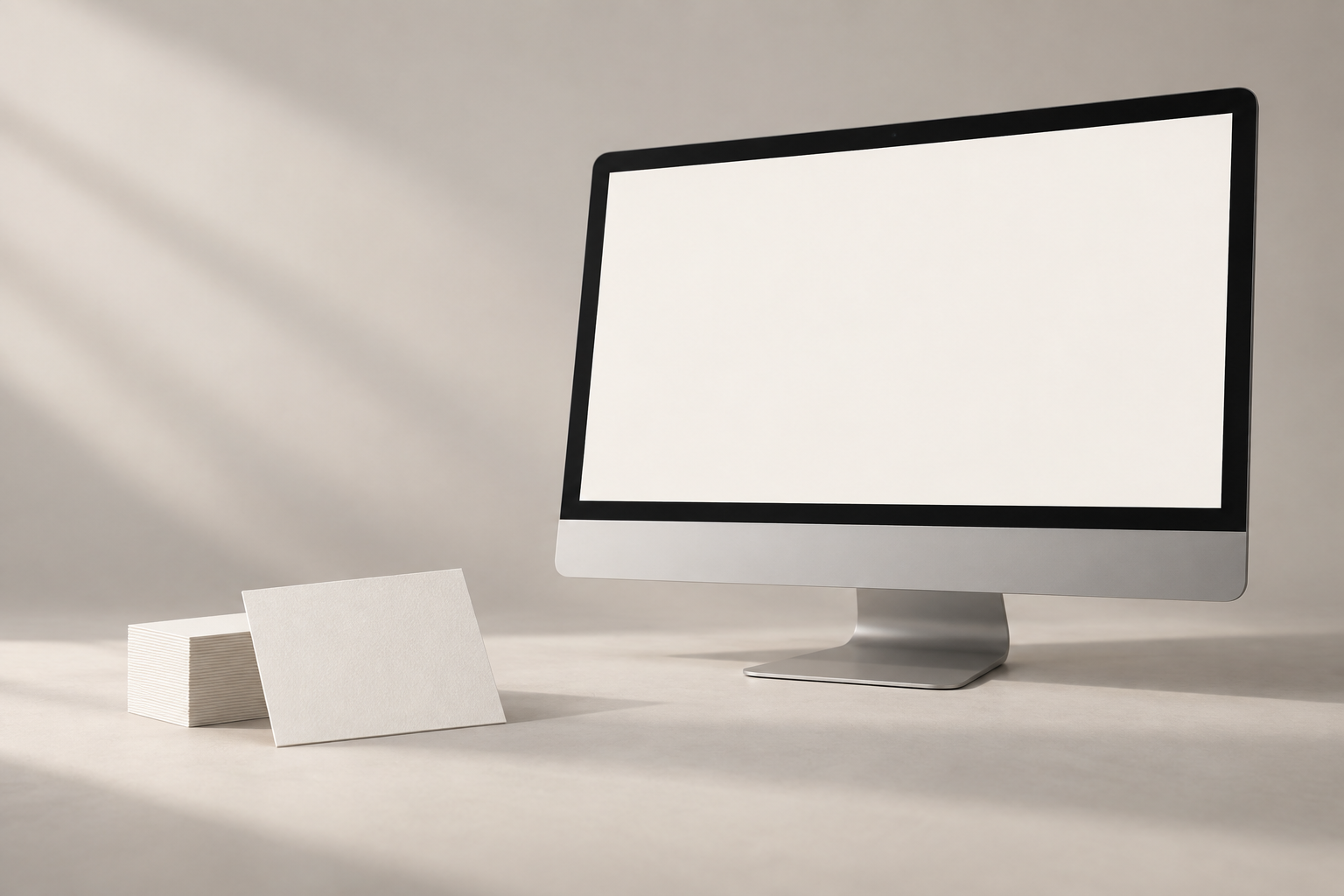 Blank business cards and a desktop computer with a blank screen, arranged in a softly lit studio
